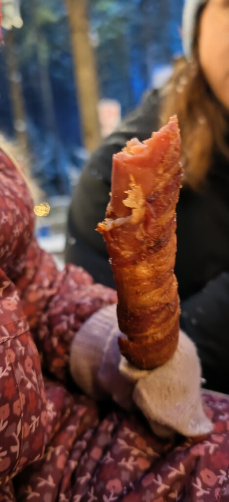 Une saucisse enrobée de bacon et trempée dans le sirop d'érable